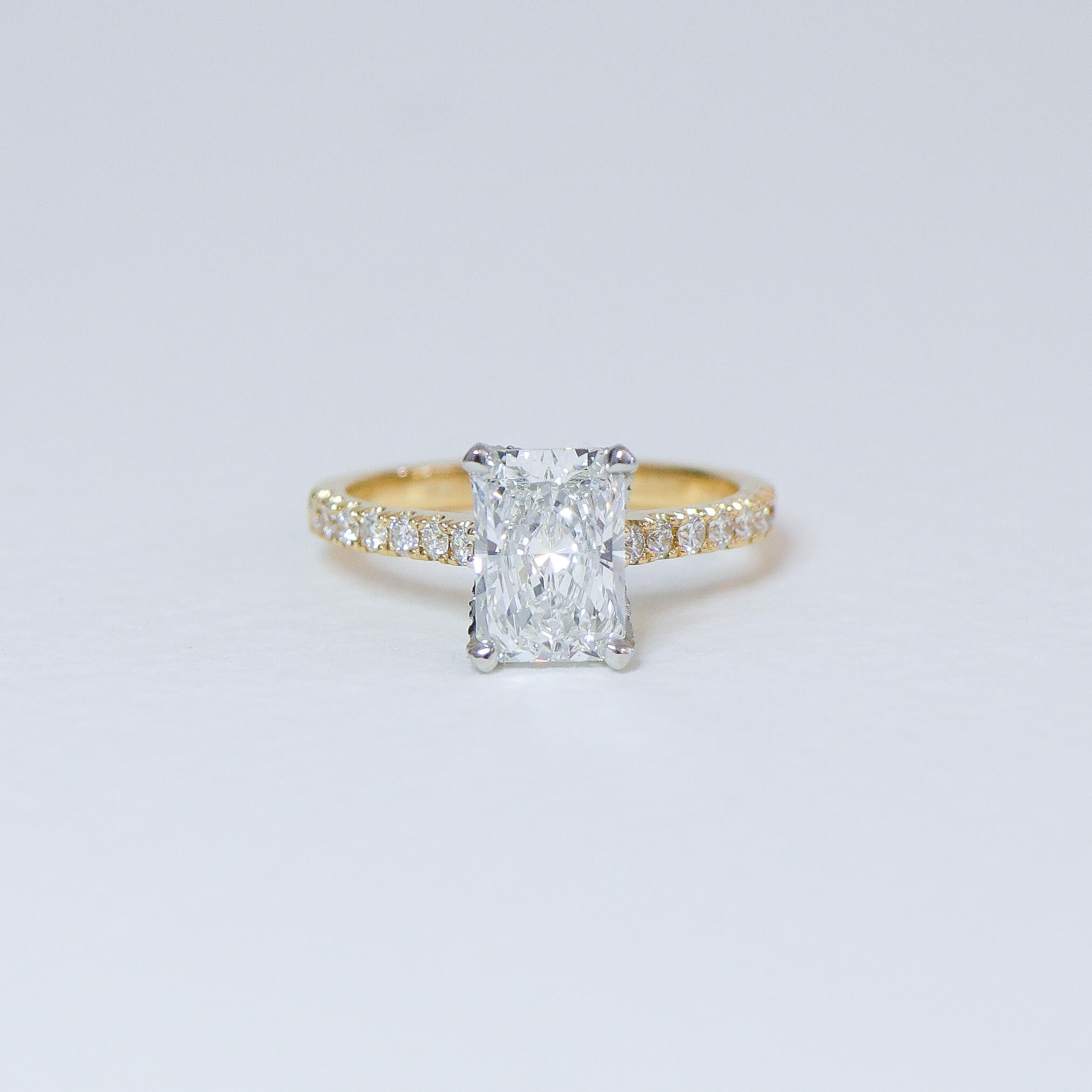 Radiant cut diamond fleur ring with diamond set band.