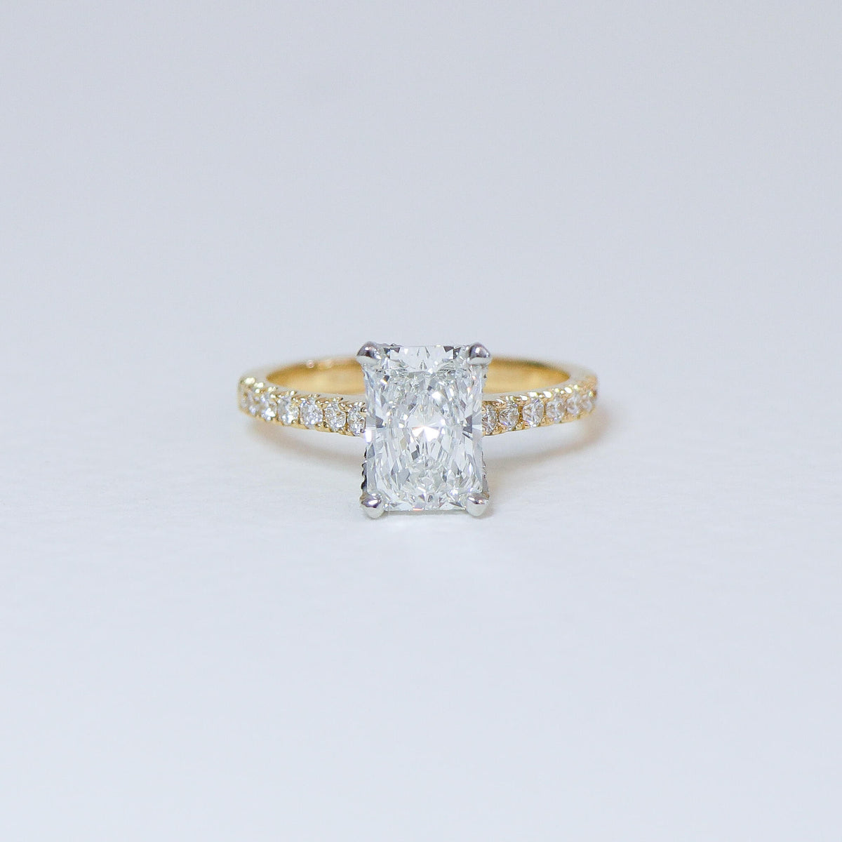 Radiant cut diamond fleur ring with diamond set band.